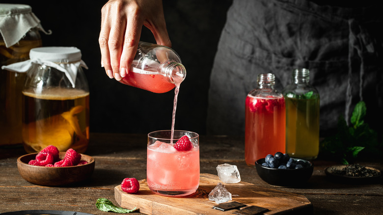 Person pouring kombucha into cocktail