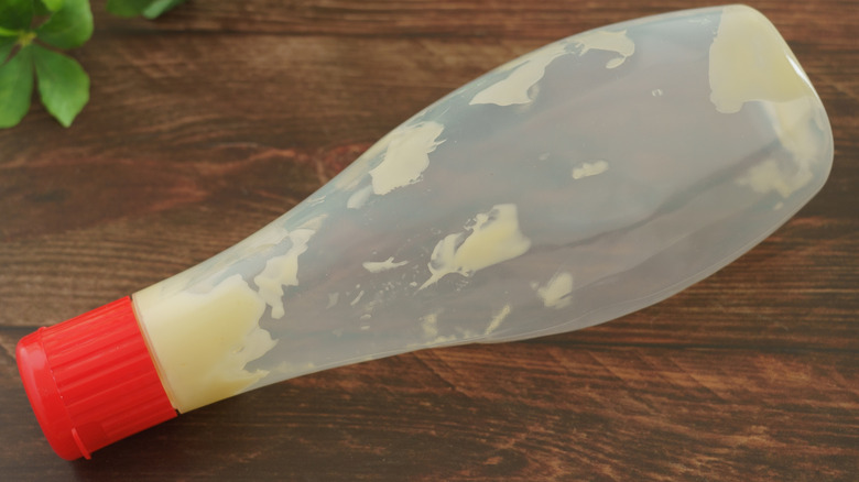 Empty mayo squeeze bottle on a wood table.