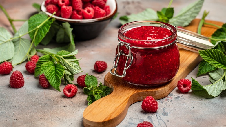 Raspberries and raspberry jam next to mint leaves