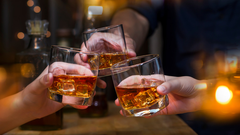 3 friends clink rocks glasses