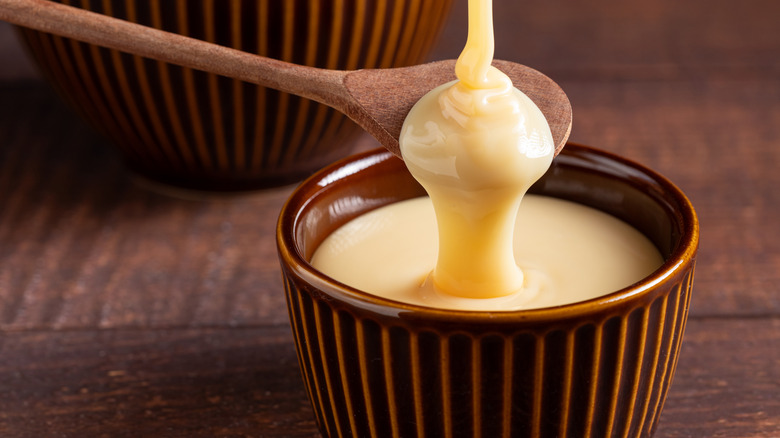 sweetened condensed milk dripping over spoon into bowl
