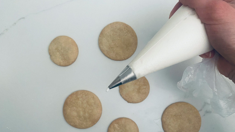 pipping bag with royal icing over cookies