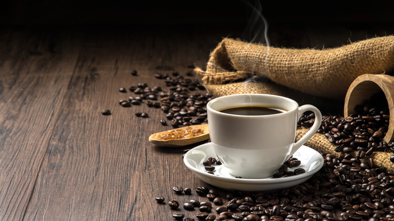White coffee mug surrounded by coffee beans