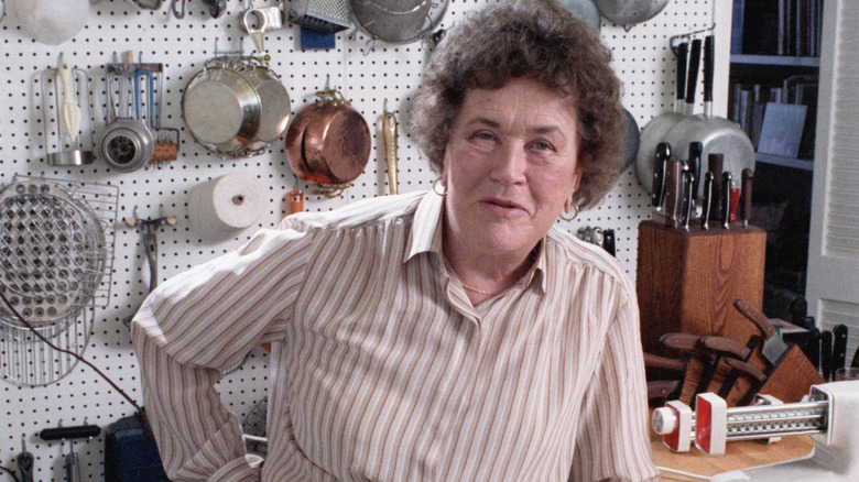 Julia Child in kitchen in front of pots and pans
