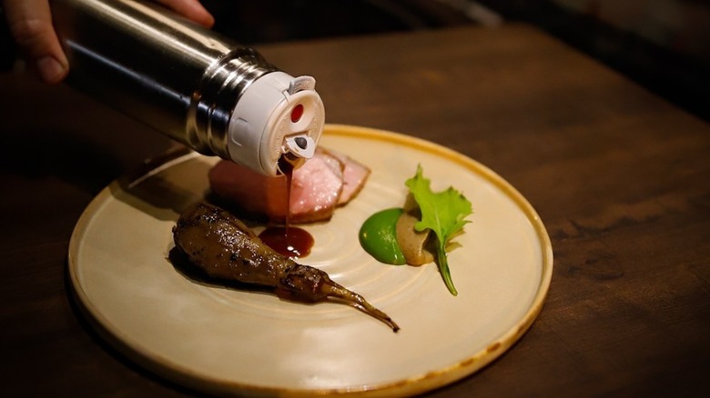 Drizzling sauce onto plated food