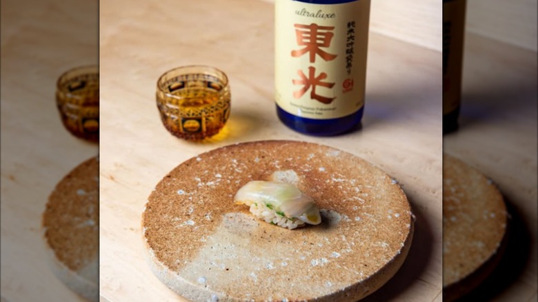 Sashimi on a dish with a bottle of saki and glass