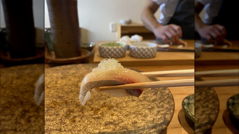 Chopsticks holding sashimi