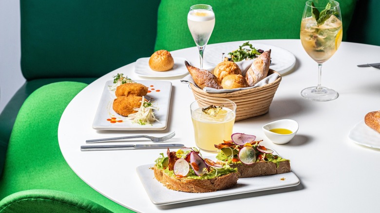 White table with various fresh-looking foods and a basket of bread