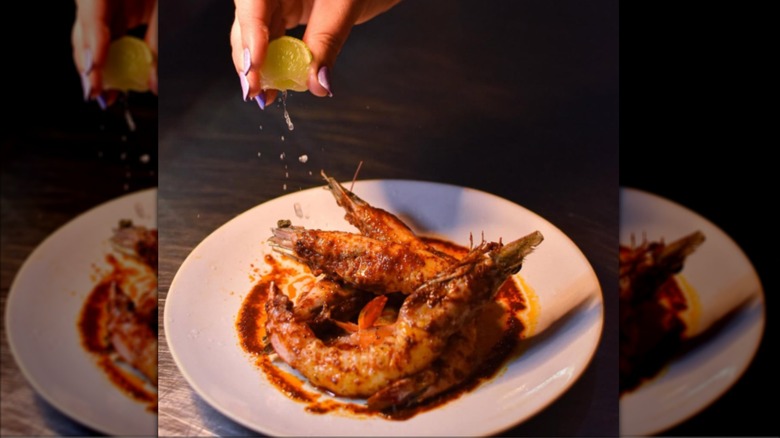 Squeezing a lime over shrimp on a white plate