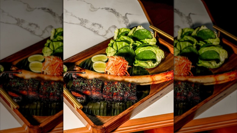 Wooden plate with steak, salad, and lime slices