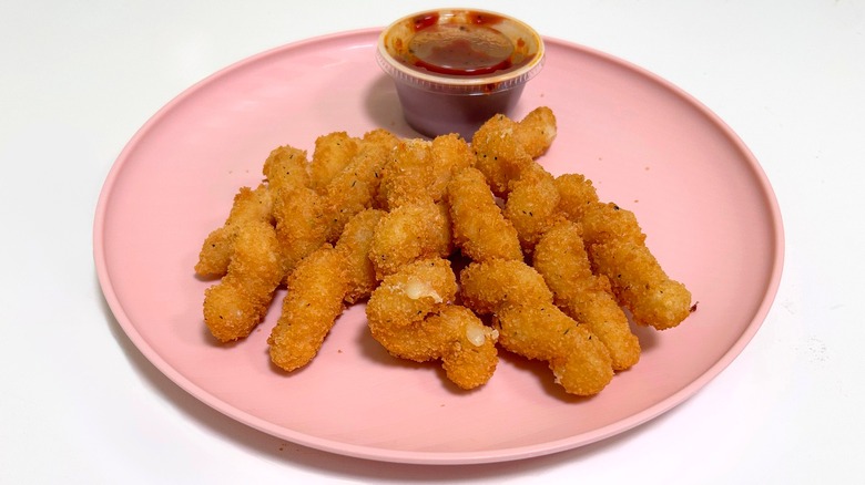 Twisted mozzarella and marinara sauce on a pink plate against a white background