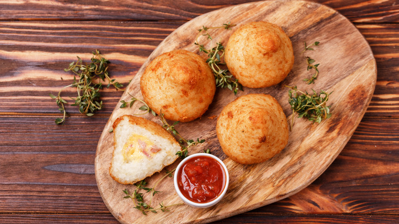 Arancini Di Riso on a wooden board with dipping sauce