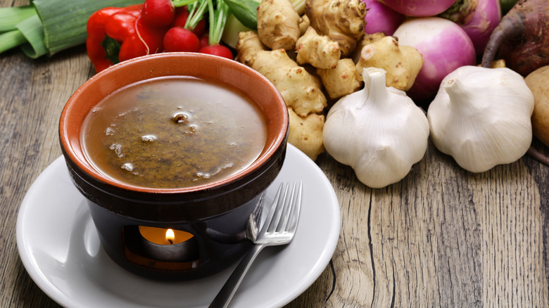 Bagna Cauda in a crock surrounded by fresh vegetables