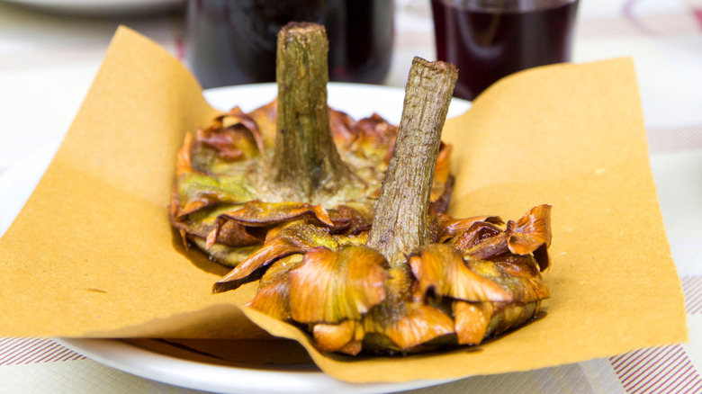 Close up of Carciofo Alla Giudia on white plate with yellow napkin