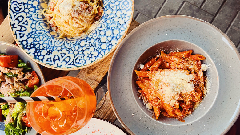 Assorted Italian dishes on decorative plates with an Aperol spritz