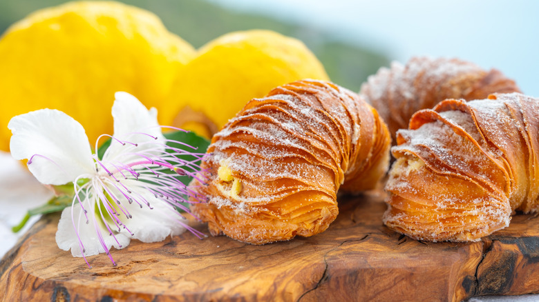 Sfogliatella on a wooden cutting board garnished with flowers and lemons