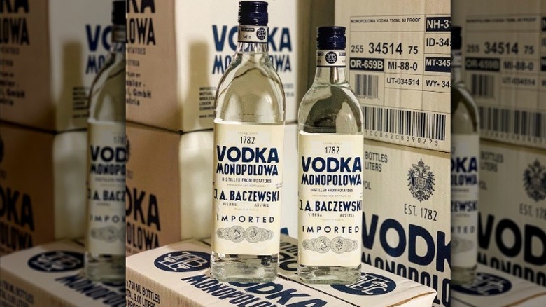 Two bottles of Monopulowa vodka on a box and in front of cases of the liquor
