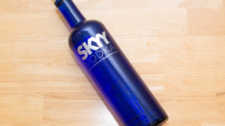 A closeup of a Skyy Vodka bottle lying on a wooden surface