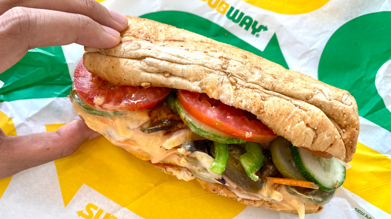 A person holding a subway sandwich