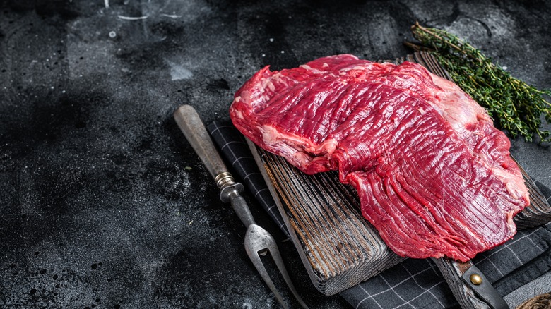 raw flap steak on a board with herbs