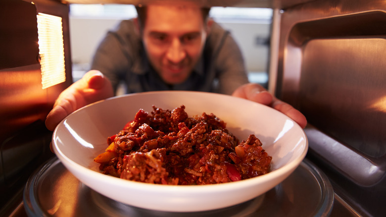 man reheating food in microwave