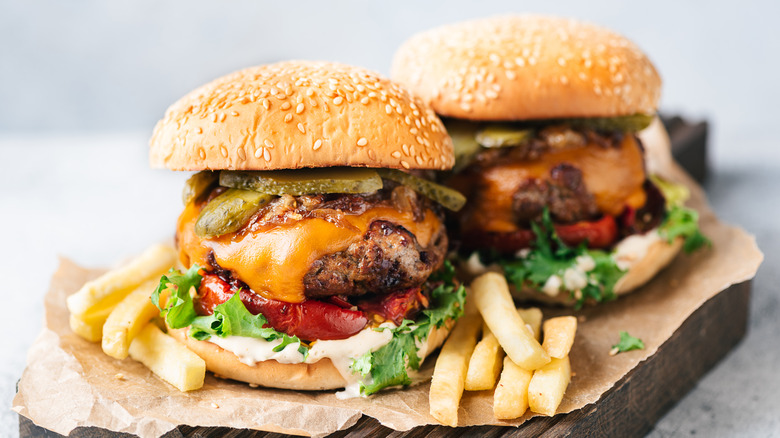 Two burgers on wooden board