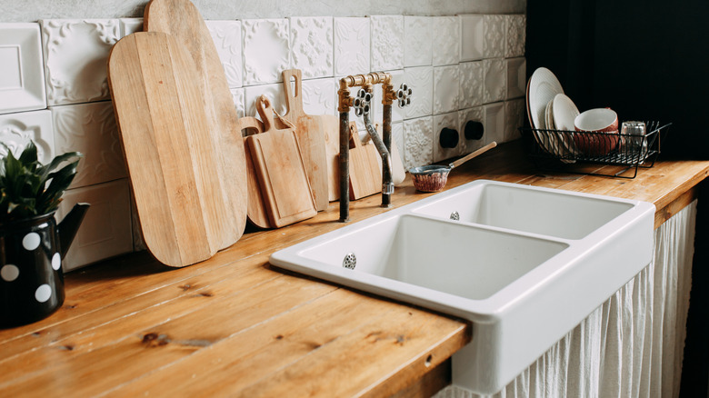 A modern industrial-style kitchen with wooden countertops and a white sink skirt