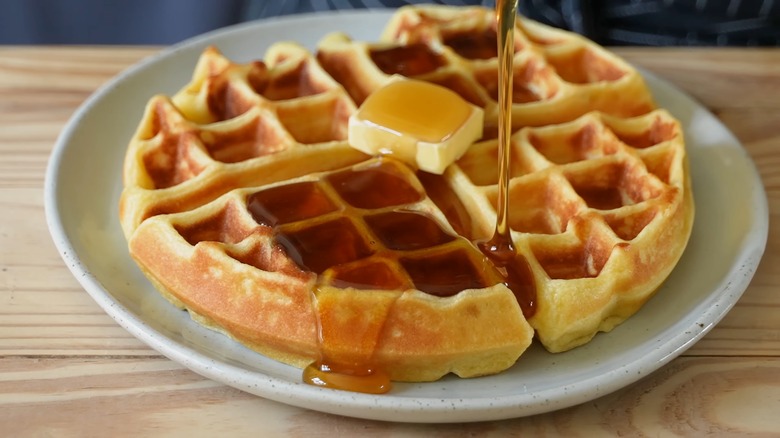 Syrup being poured on a waffle