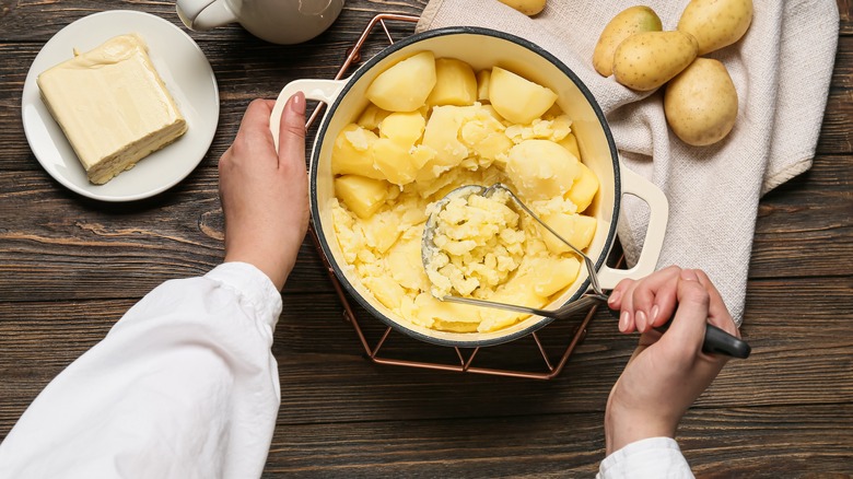 Person hand mashing potatoes