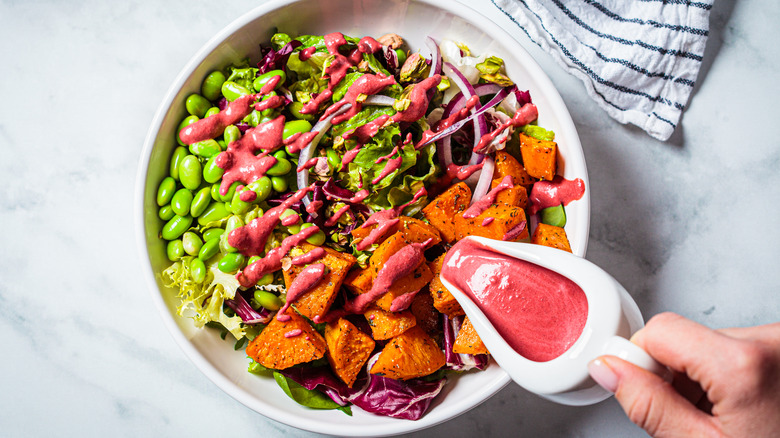 Pink dressing pouring onto salad