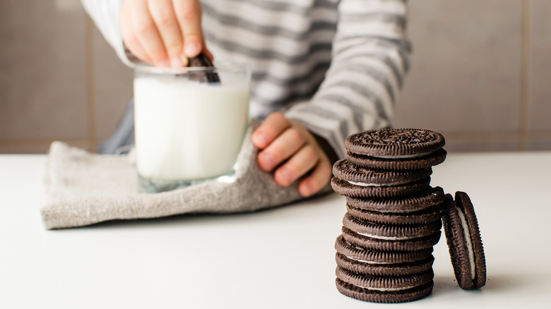 someone dunking Oreo cookie in milk
