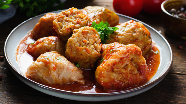 Cabbage rolls with tomato sauce on a plate placed on a wooden table
