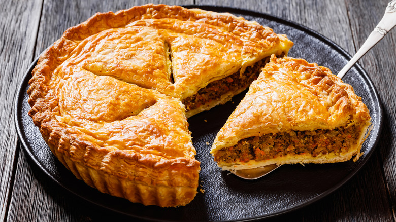 Sliced hamburger pie on a black plate placed on a wooden table