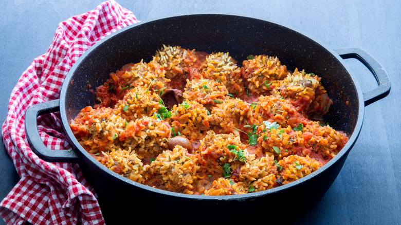Old-fashioned porcupine meatballs in a skillet placed on a blue table with a napkin on the side