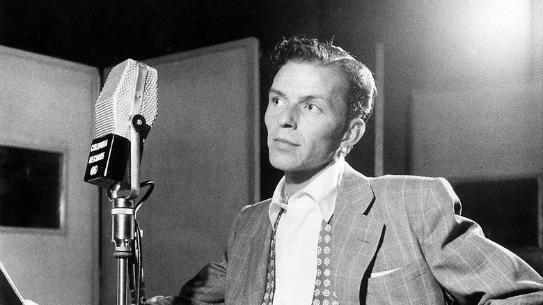 Frank Sinatra standing in front of old-fashioned microphone