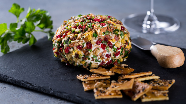 Cheese ball on black slate with crackers