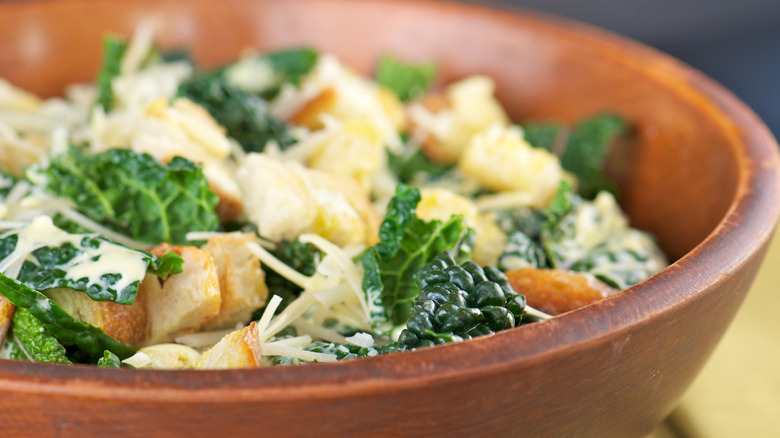 Close up of kale Caesar salad in wooden bowl