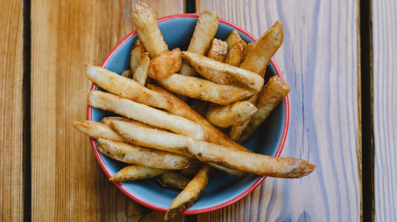 A view of fries from above, in a bowl on a wooden table
