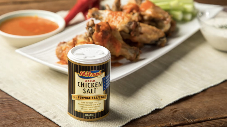 A shaker of Mitani Chicken Salt in front of a plate of chicken