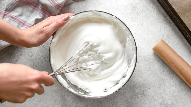 Hands whisking cream in bowl 