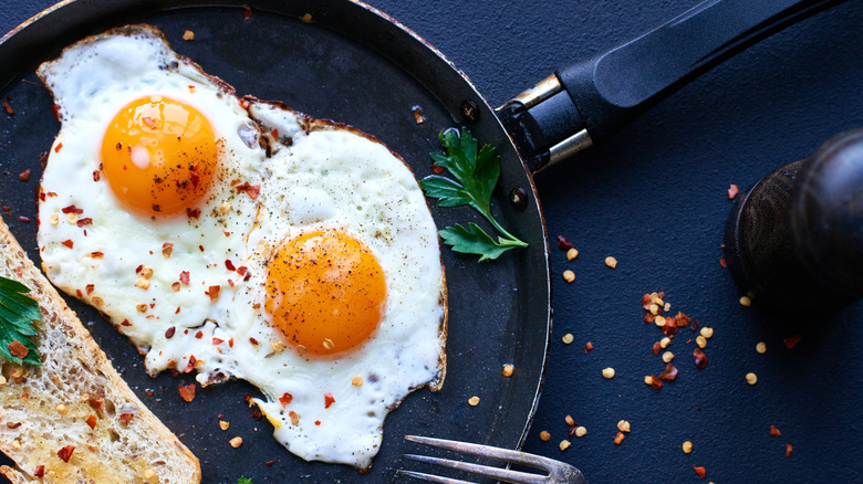 Fried eggs with chili flakes on pan