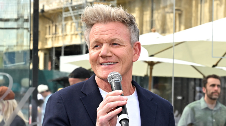 Gordon Ramsay smiling and holding a microphone