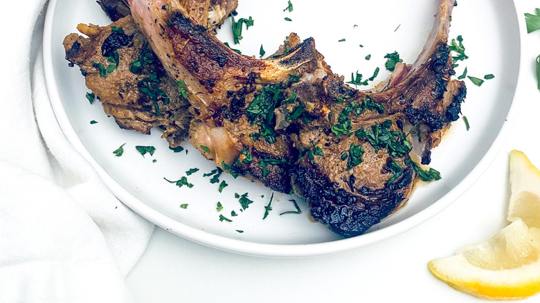 Lamb chops on white plate with lemon slice