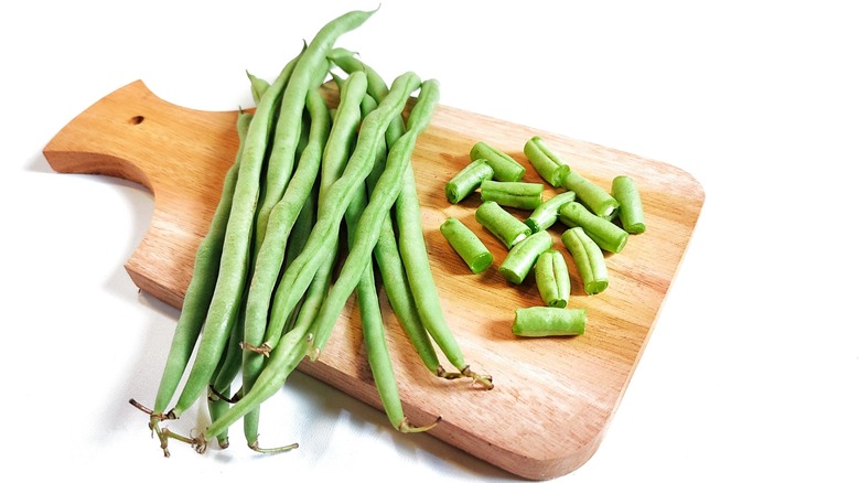 Freshly prepared green beans on a wooden cutting board