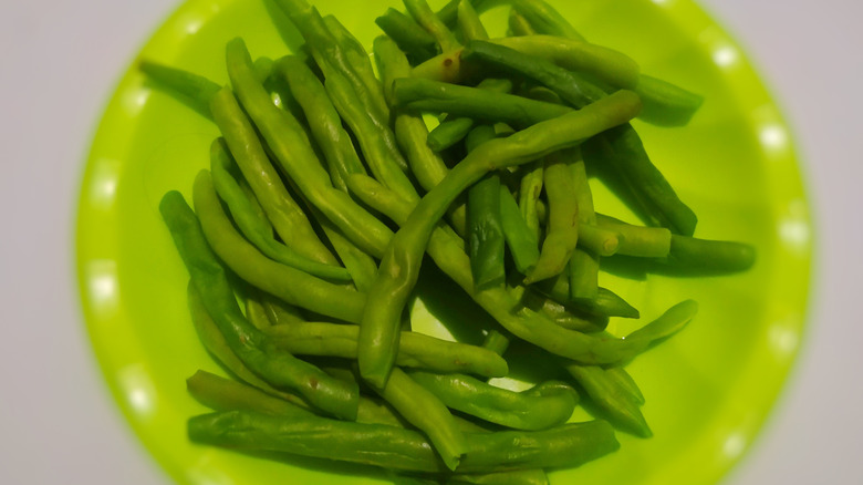 Boiled green beans in a plastic green bowl