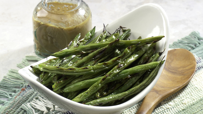 Grilled green beans in white oval bowl with vinaigrette