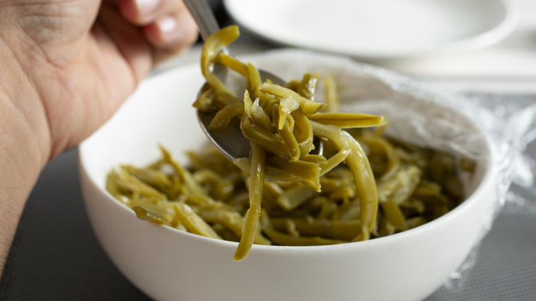 White bowl of mushy, overcooked green beans