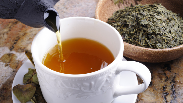 Pouring green tea into cup