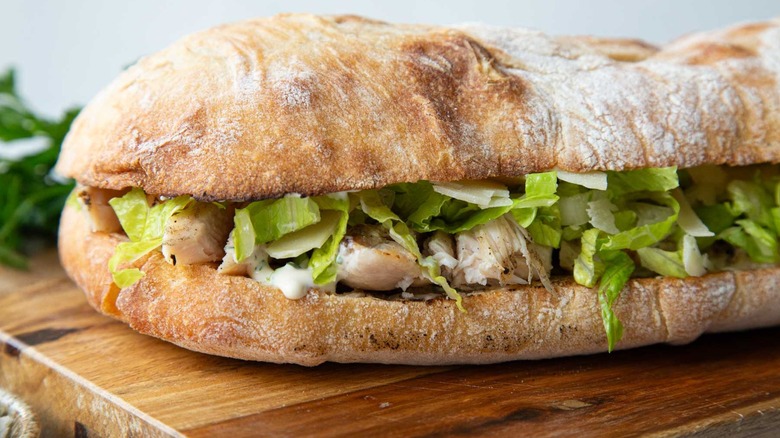Chicken sandwich with lettuce on a wooden board