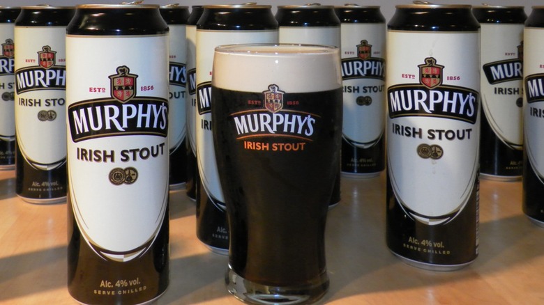 Glass and cans of Murphy's Irish Stout on a counter
